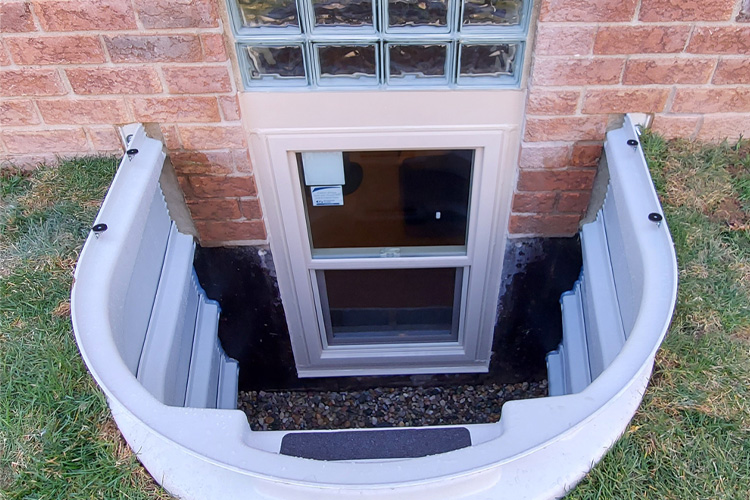 Exterior view of a Wellcraft 5600 well with escape window and two rows of glass block at a red brick home in Utica, Michigan.
